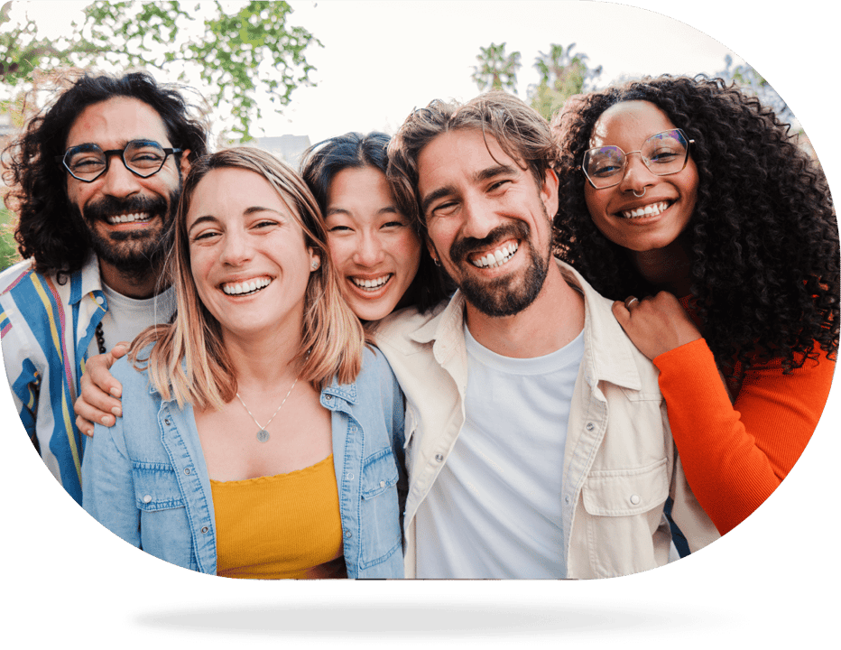 A smiling group of five people together outdoors.